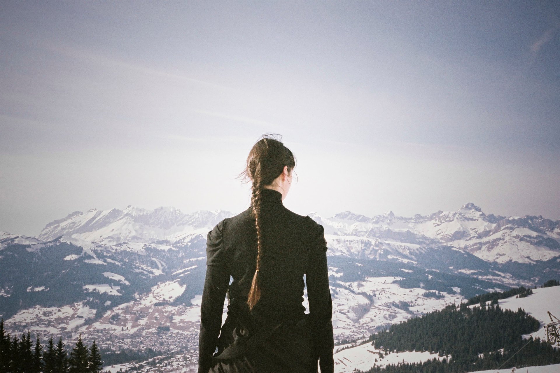 Woman with braid, dark clothing, snowy alpine panorama