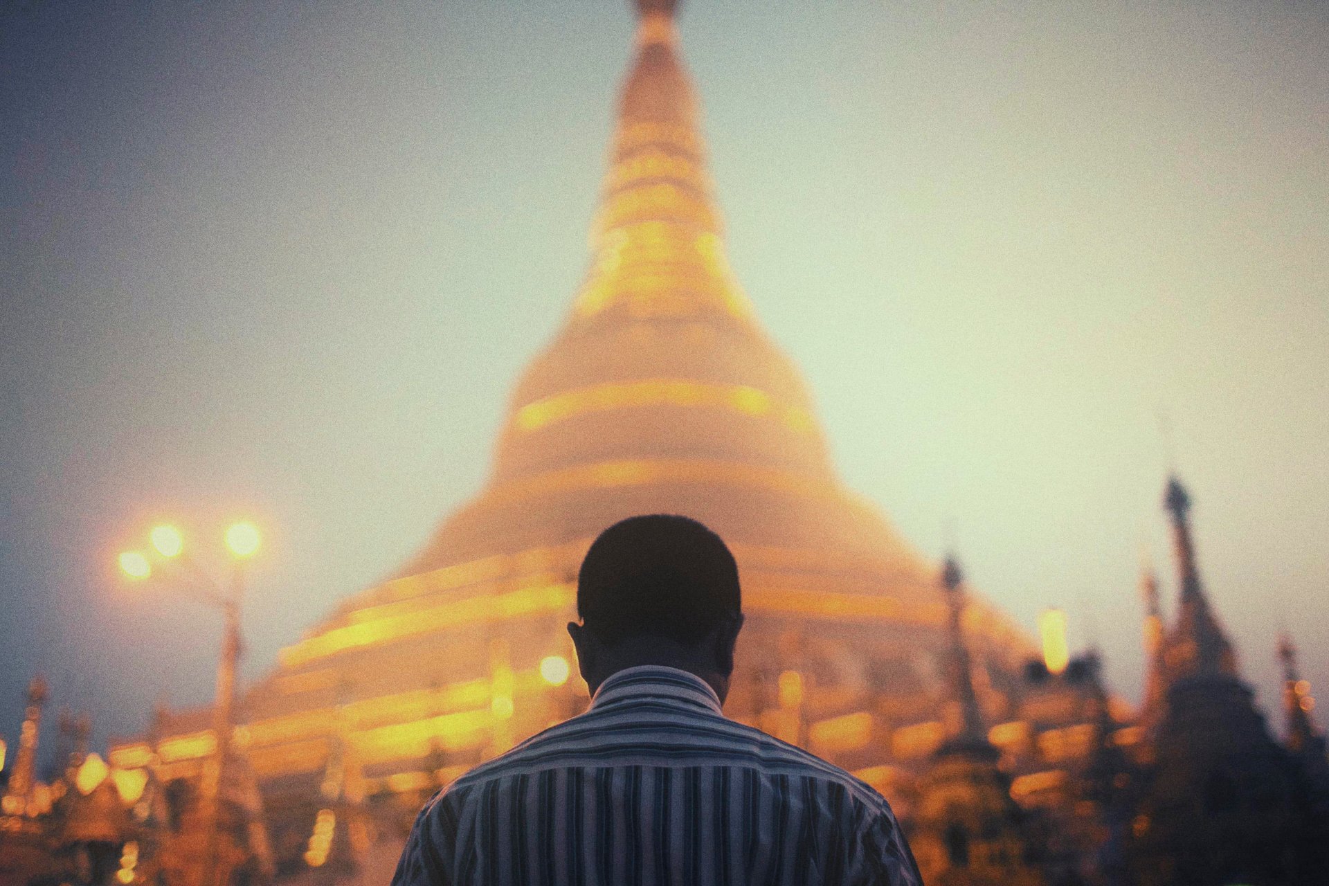 Man before golden Shwedagon Pagoda, Myanmar, dusk