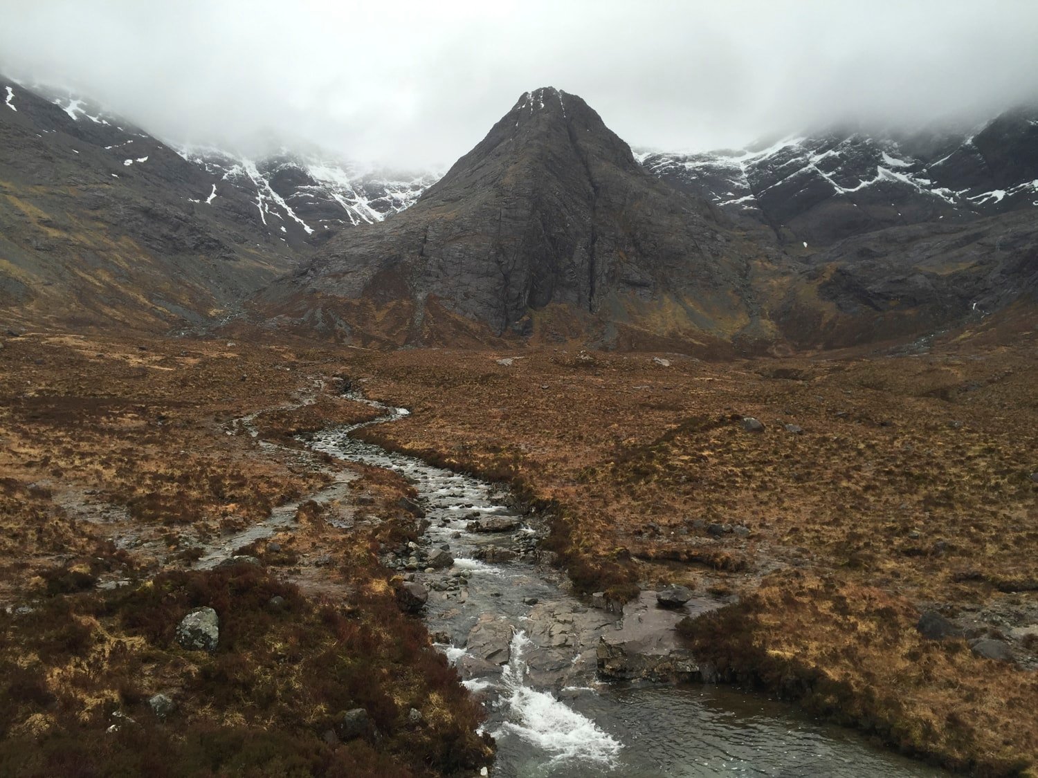 Cuillin peak with stream cutting through moorland, snow