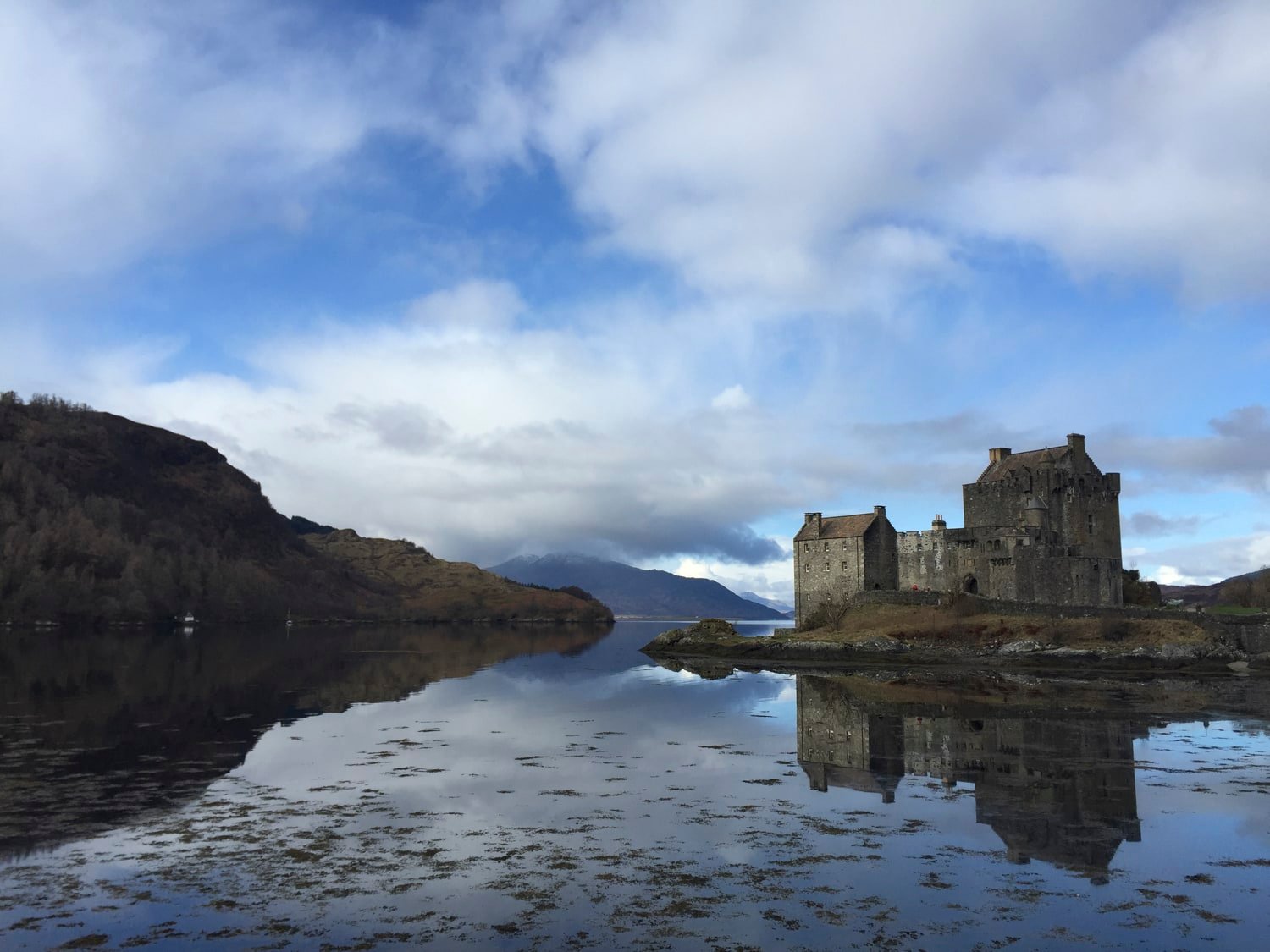 Eilean Donan Castle reflected in still water, blue sky